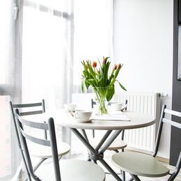 Eine helle Wohnung, ein Esstisch mit einer Vase und Tulpen und ein paar Kaffeetasen