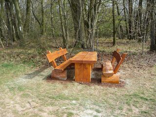 EIne Sitzgruppe aus Holz im Wald: Zwei Bänke und ein Tisch